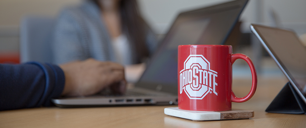 Ohio State mug on a desk next to a laptop and tablet