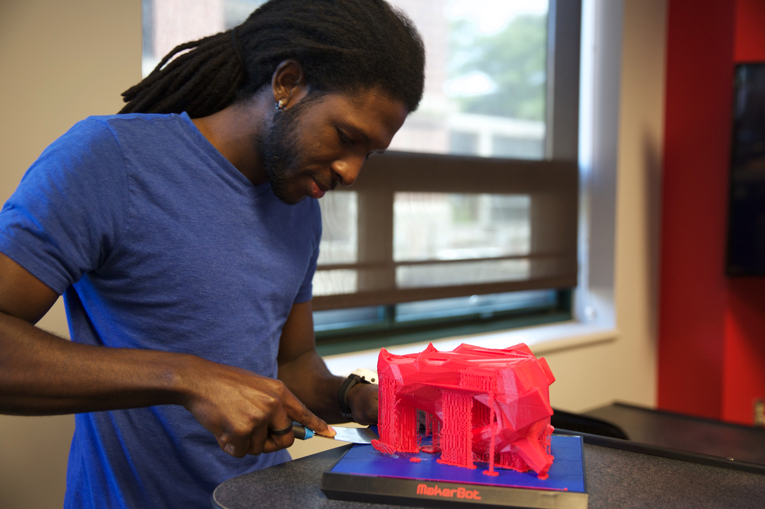 A man peeling a 3D printed item off a MakerBot plat