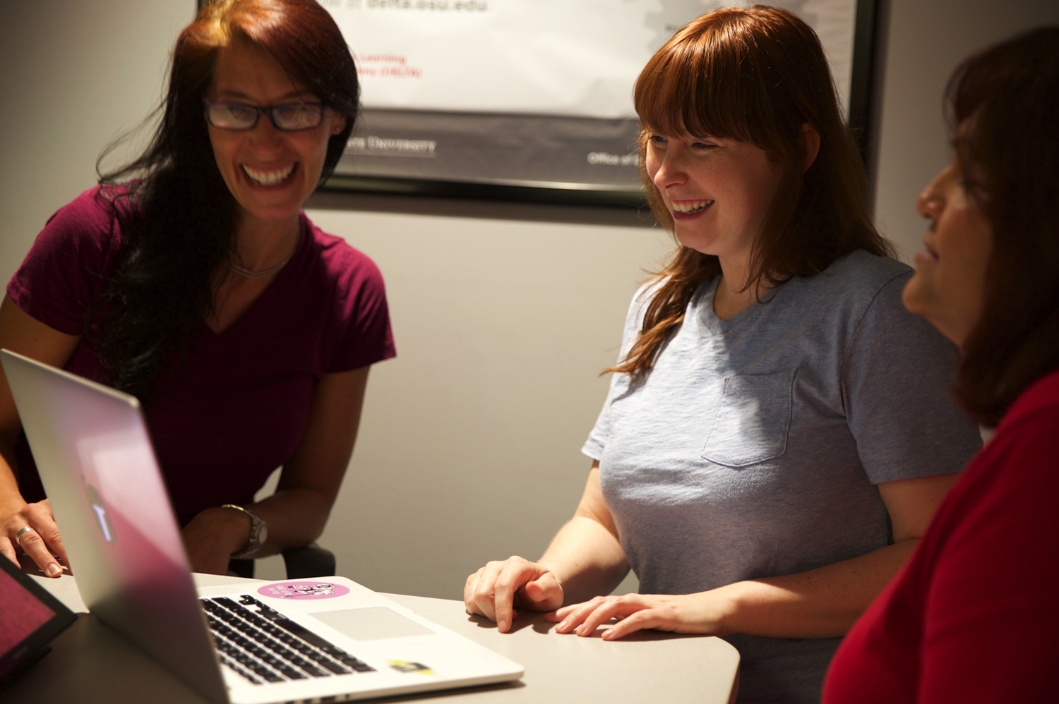 A group of people smiling and looking at a laptop together