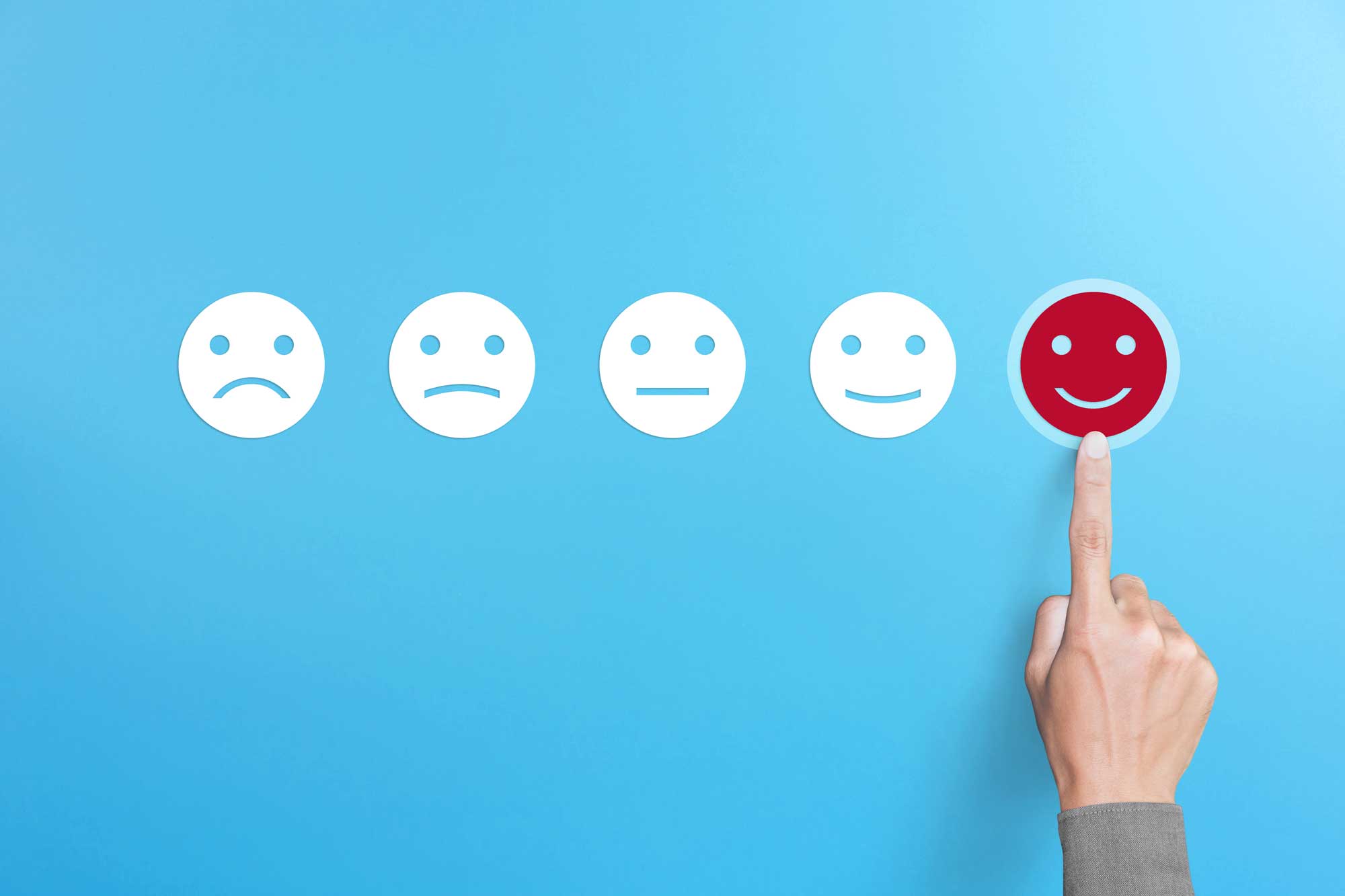 Hand pointing at smiley face in a row of faces showing different levels of satisfaction
