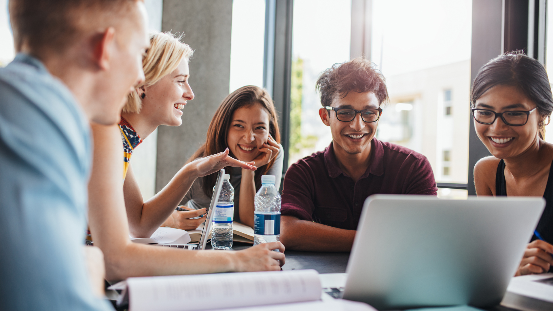 A group of students smiling and looking at a laptop together