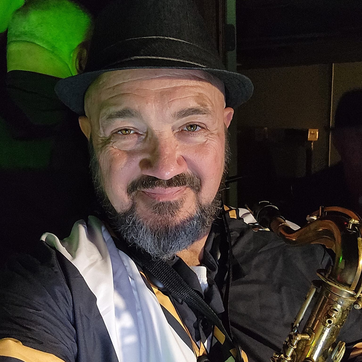 Aaron wearing a hat and holding a saxophone.
