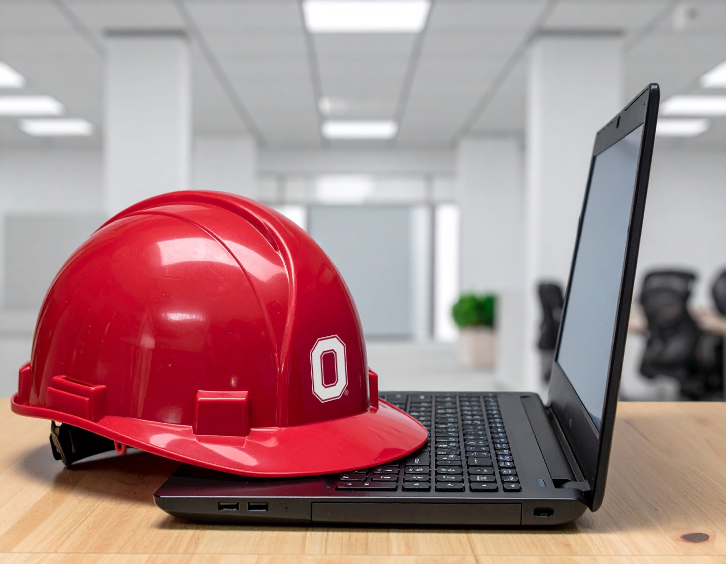 Construction hat with a block O laying across an open laptop computer.