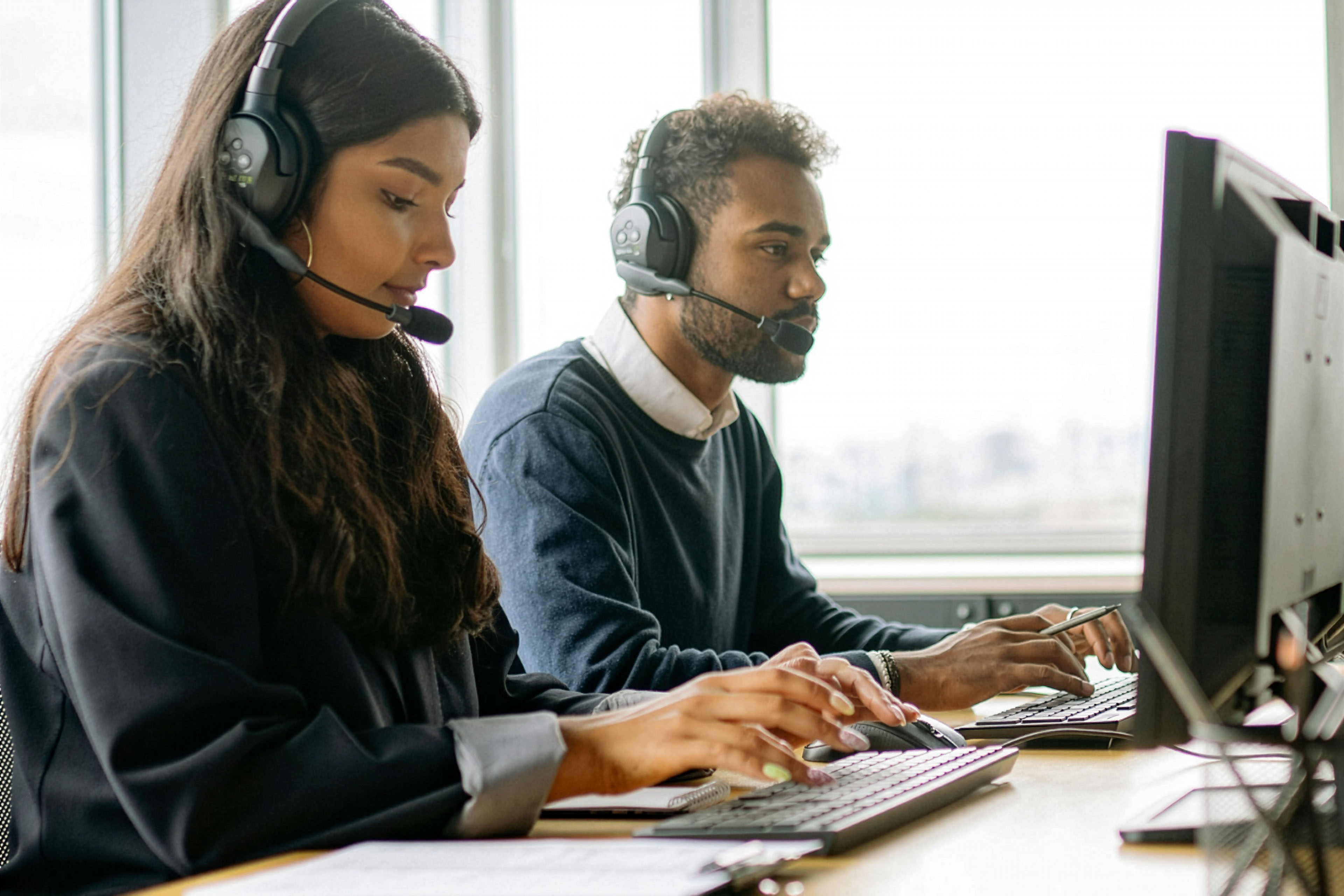 Help Desk techs wearing headsets and using computers