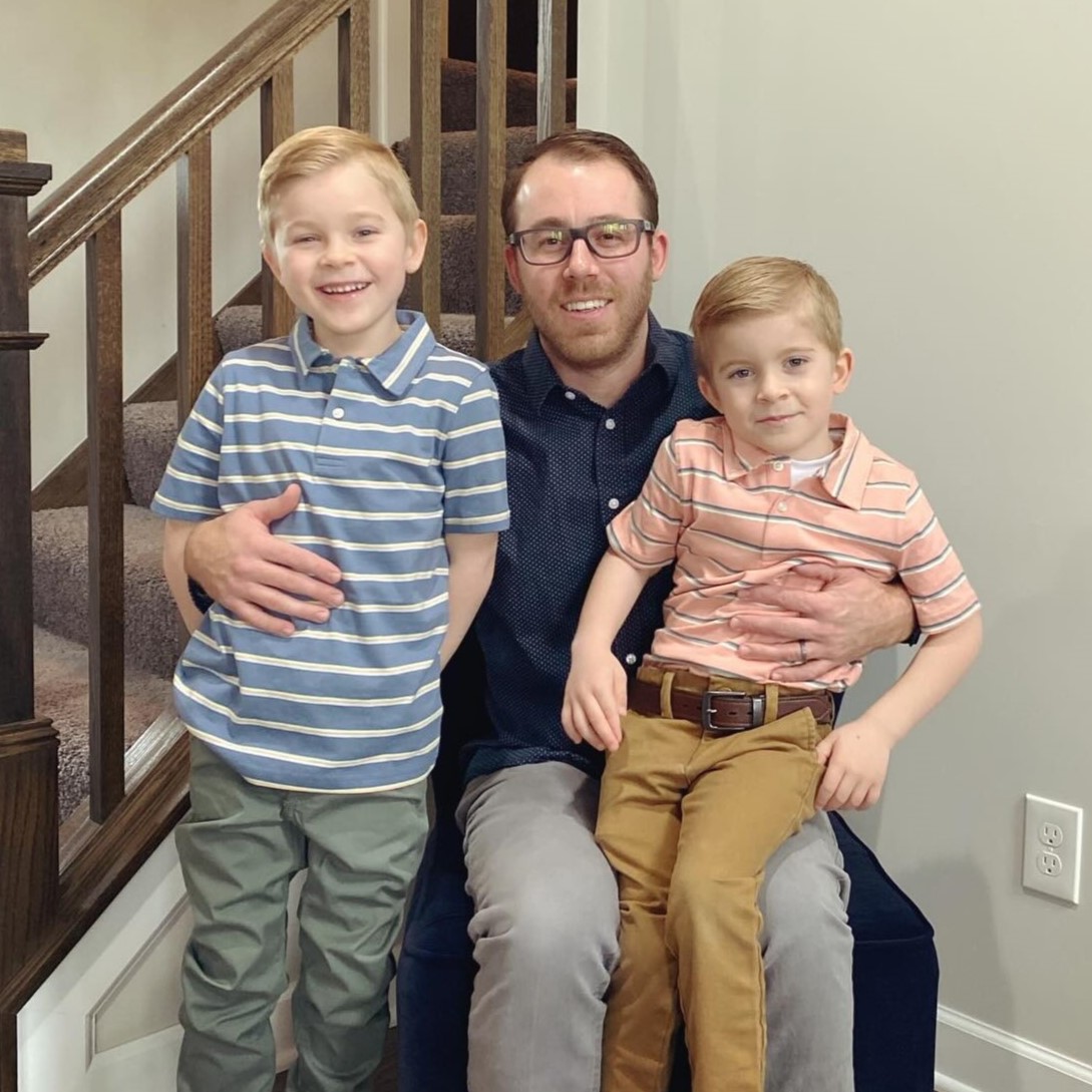Travis sitting with his two young sons on his lap.