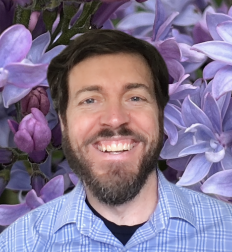 Dave smiles on a Zoom call amidst a background of purple flowers