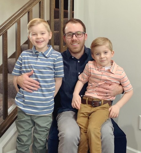 Travis sitting with his two young sons on his lap.