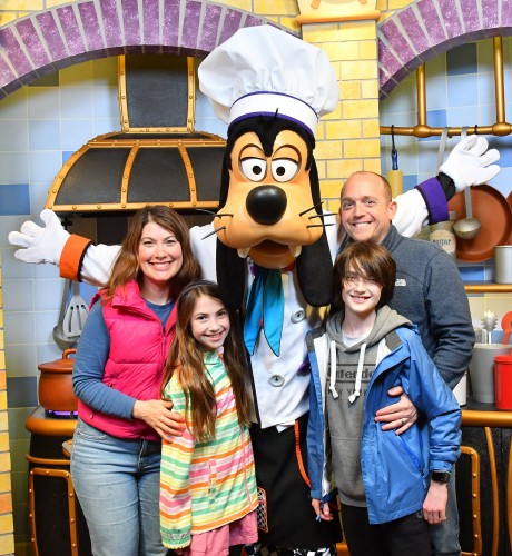 Lauren, her husband and their two kids pose with Goofy during a family vacation.