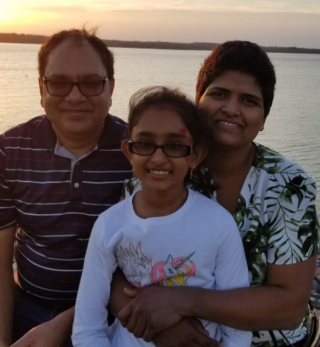 Sravani poses for a photo on the beach with her husband and daughter