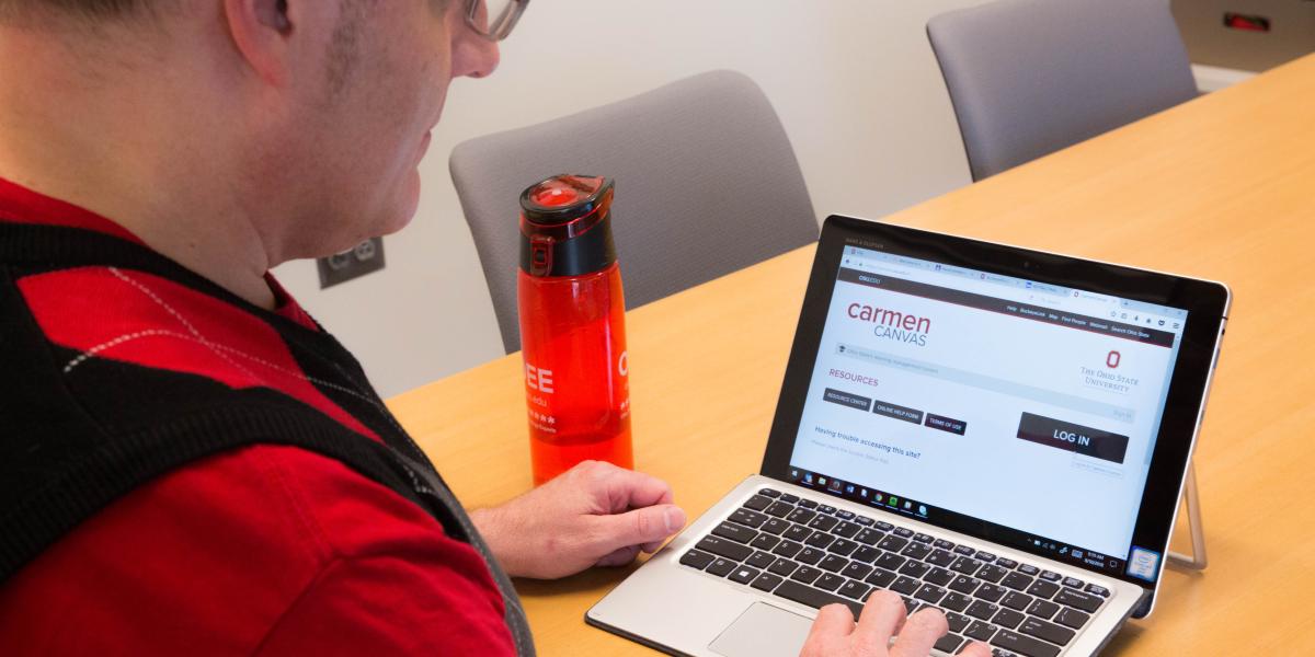 Person using a tablet with the CarmenCanvas login page on the screen