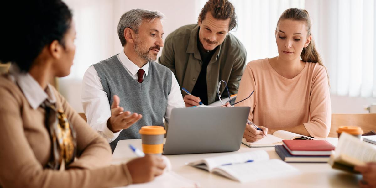 Group of people collaborating around a laptop