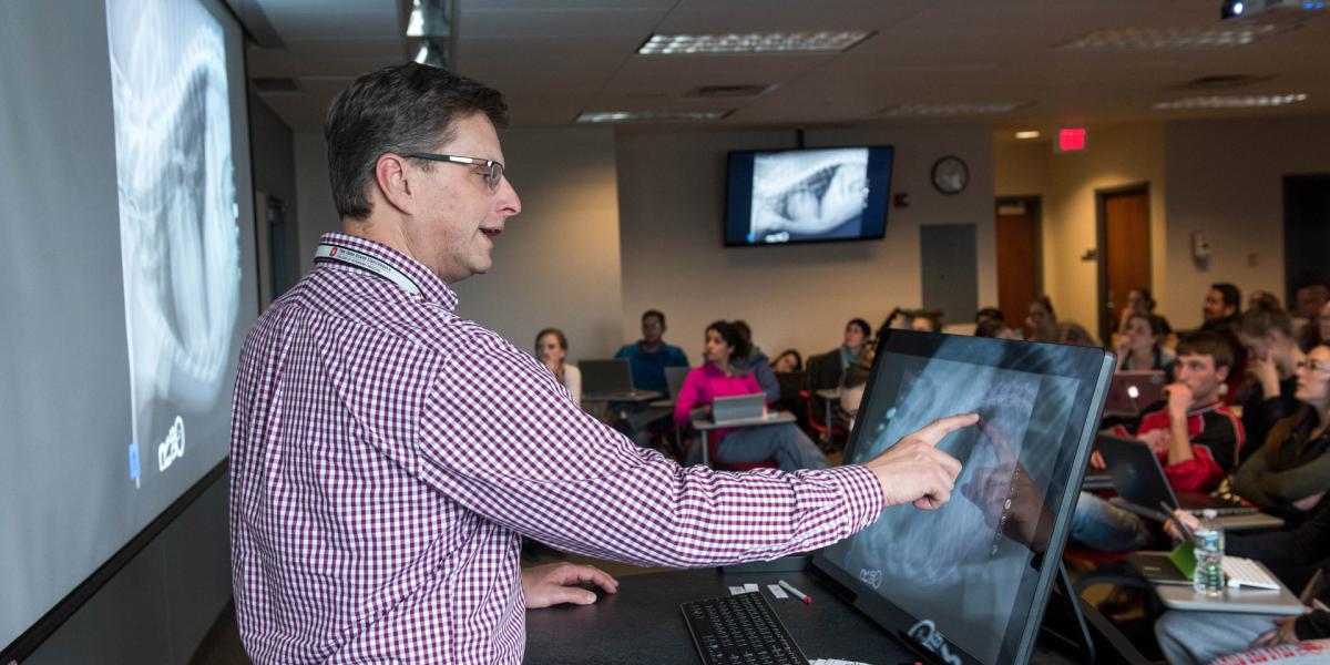 Instructor using touch screen in front of classroom of students