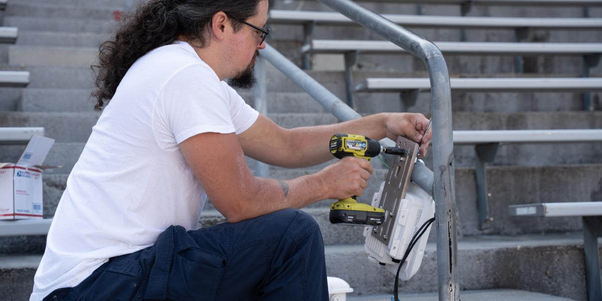 A man drilling an AP to a handrail inside Ohio Stadium