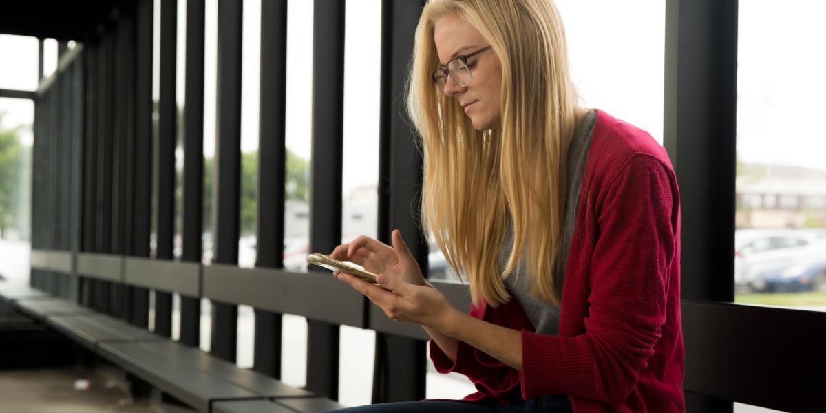 Person using a smart phone while waiting at a bus stop