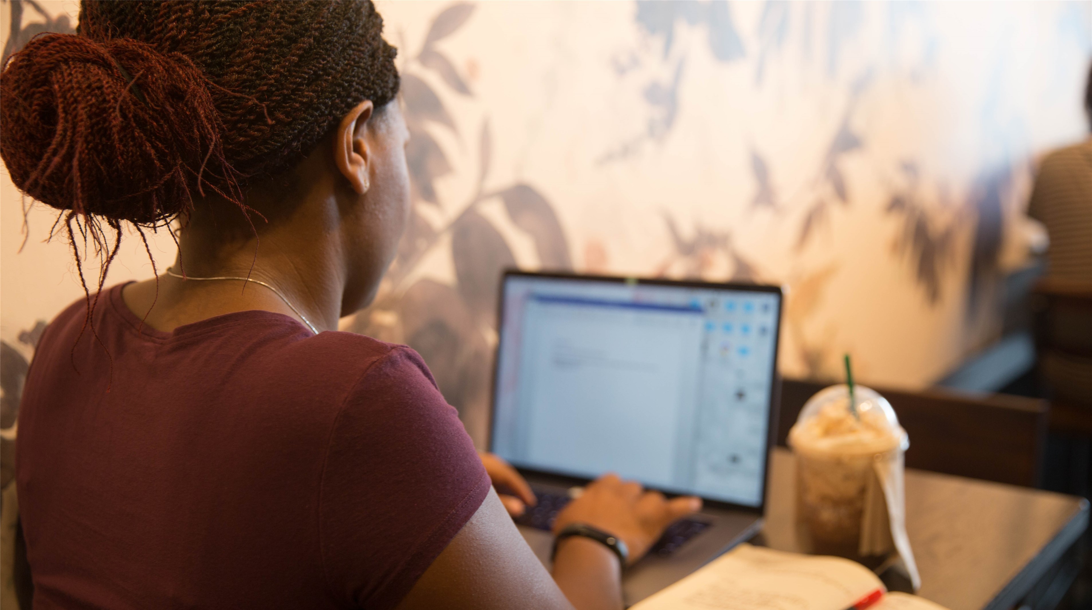 Decorative image of woman using laptop in a coffee shop