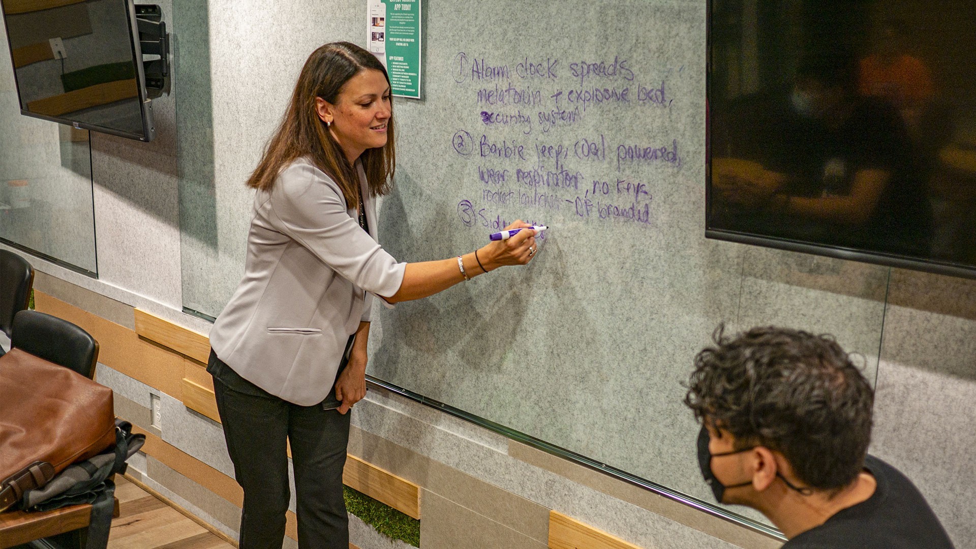 Presenter writing on a dry erase wall