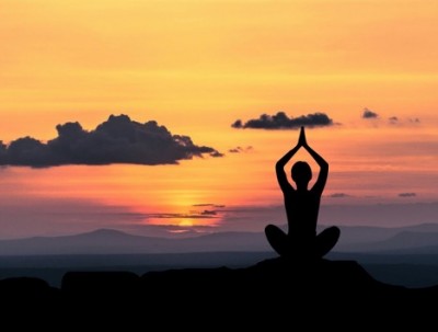 Person performing yoga in front of a sunset