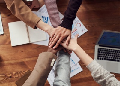 People With Hands Together Over Wooden Table