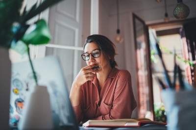 A person sitting at a desk looking at laptop screen.