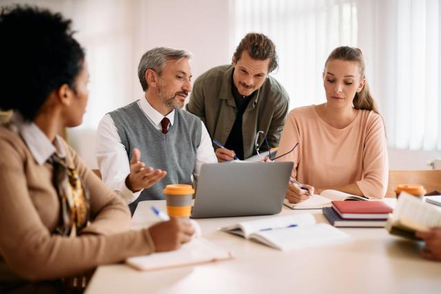 Group of people collaborating around a laptop