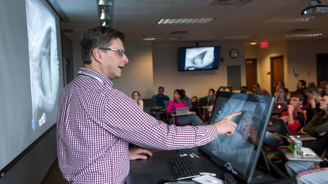 Instructor using touch screen in front of classroom of students