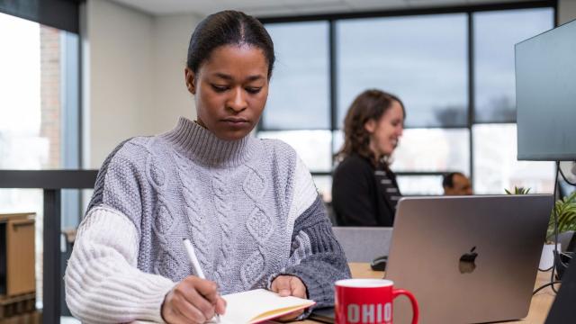 Woman writing while sitting at a desk