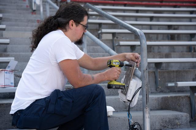 A man drilling an AP to a handrail inside Ohio Stadium