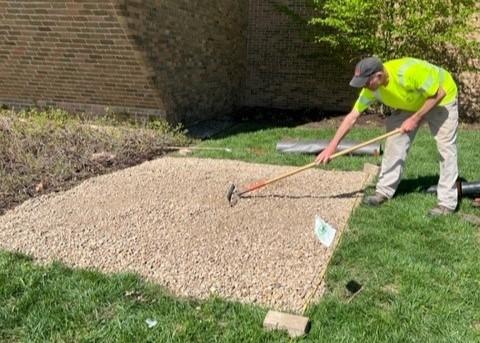 Facilities representative installing gravel garden bed outside of Mount Hall.