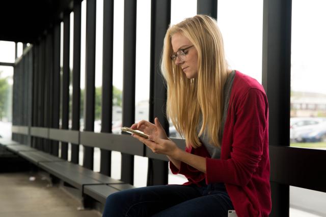 Person using a smart phone while waiting at a bus stop