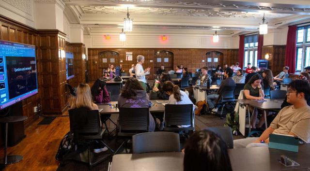 Instructor in the center of a classroom full of students seated at tables