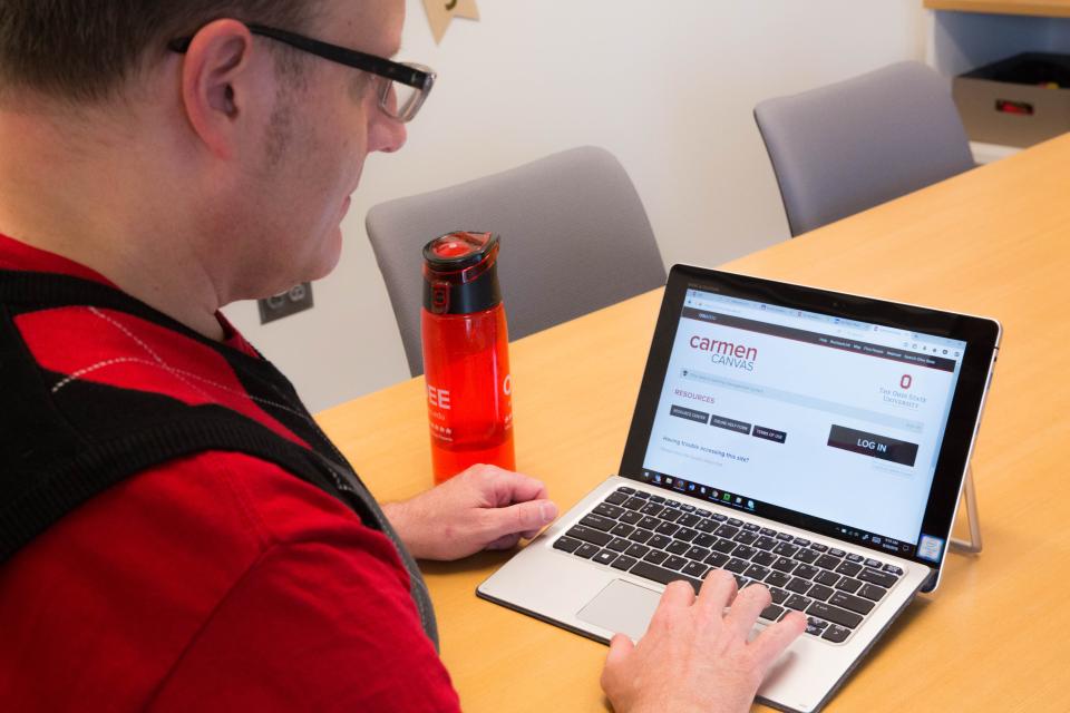 Person using a tablet with the CarmenCanvas login page on the screen