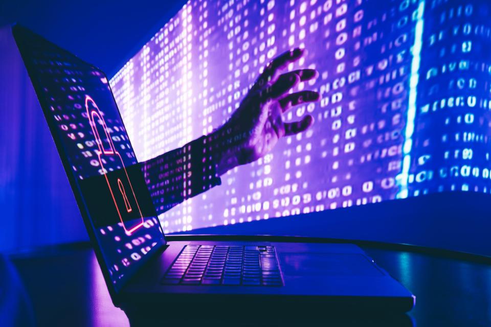 A hand reaching out of a laptop screen.