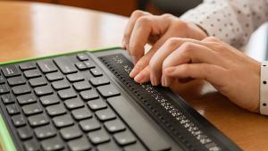 A blind woman using a Braille keyboard to interact with digital content